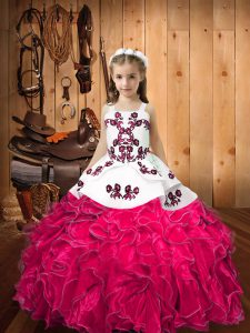 Elegante sin mangas hasta el suelo con organza y cordones en un vestido de niña pequeña en rosa intenso con bordados y volantes