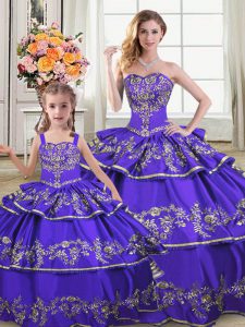 El simple bordado sin mangas de color púrpura y las capas con volantes ata el vestido de quinceañera